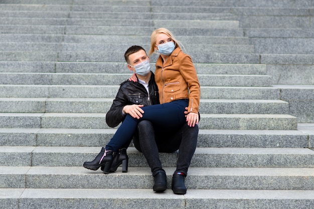 Para w maskach ochronnych wychodzi na spacer po mieście w pobliżu budynku biznesowego w czasie kwarantanny. Koncepcja koronawirusa.