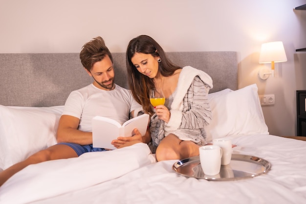 Para w piżamie szukająca hoteli lub wycieczek z komputera przy śniadaniu
