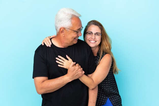 Para w średnim wieku na niebieskim tle śmiejąca się i przytulająca