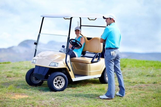 Zdjęcie para wózków golfowych lub golferzy na boisku do ćwiczeń fizycznych lub ćwiczeń zespołowych na zielonym polu kobieta kierowca mężczyzna golfista lub sportowcy trenujący w grze ćwiczą lub jeżdżą razem w pojeździe