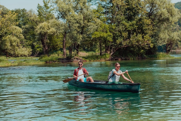 Para żądnych przygód przyjaciół odkrywców pływa kajakiem po dzikiej rzece otoczonej piękną przyrodą.