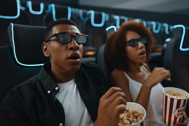 Para zakochanych przyjaciół ogląda film z popcornem w kinie