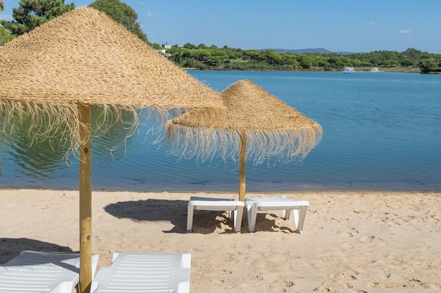 Zdjęcie parasole i leżaki na plaży w pobliżu jeziora. letni wypoczynek.