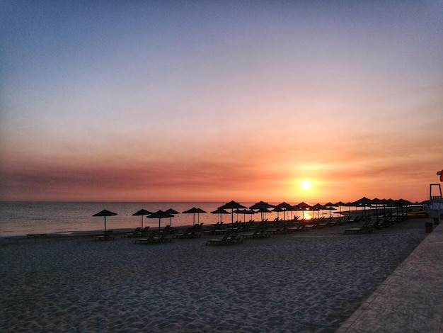 parasole przy leżakach na plaży podczas zachodu słońca