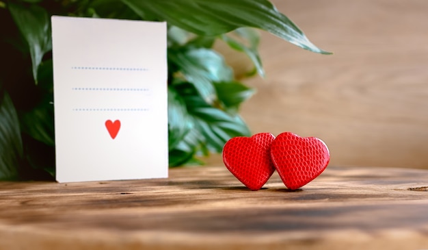 Parę czerwonych serc na drewnianym tle rustykalnym i kartkę z życzeniami na Walentynki. Koncepcja na walentynki, ślub, szczęście rodzinne, światowy dzień serca, miłość, rodzina. Skopiuj miejsce na tekst