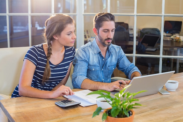 Partnerzy pracujący przy biurku za pomocą laptopa w biurze