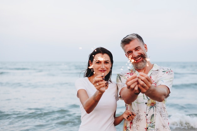 Pary odświętność z sparklers przy plażą