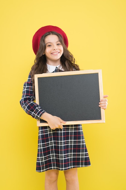 Paryskie dziecko na żółtej kopii miejsce dziecko z pustą tablicą szczęśliwa dziewczyna z długimi kręconymi włosami w reklamie beretu mała dziewczynka we francuskim berecie tablica informacyjna tutaj jest przydatna informacja