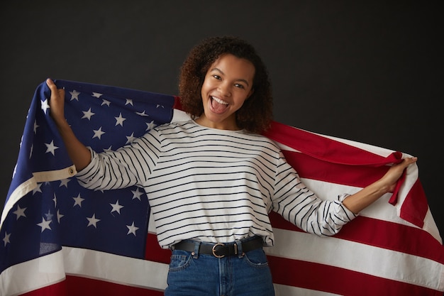 Pasa w górę portret młodej dziewczyny afroamerykańskiej trzymającej amerykańską flagę podczas pozowania