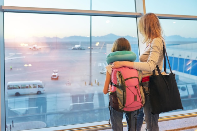 Pasażerowie lotniska rodzina matka i córka dziecko patrzące na samoloty w panoramicznym oknie