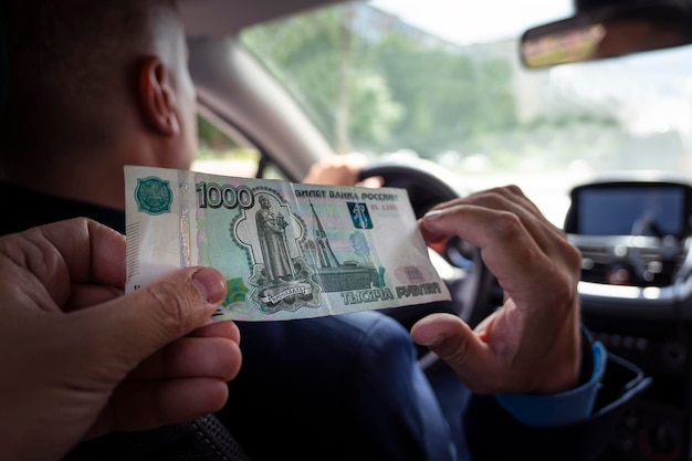 Pasażerowie płacą opłaty za obsługę męskim taksówkarzom Klient płaci za podróż w rublach Rachunek 1000 rubli w męskiej dłoni