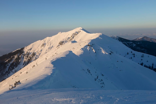Pasmo górskie jest pokryte śniegiem w promieniach porannego słońca