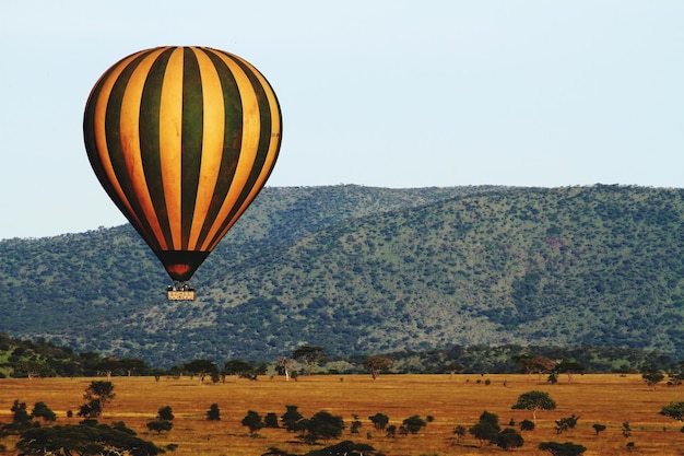 Zdjęcie pasowy balon na gorące powietrze latający nad krajobrazem na czystym niebie