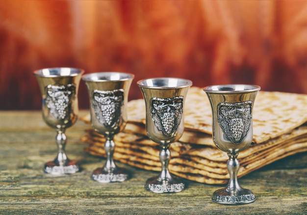 Passover tła cztery szkła wina i matzoh żydowskiego wakacyjnego chleba nad drewnianą deską.