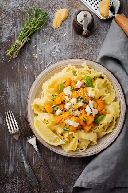 Pasta Mafaldine Napoletane Z Pieczoną Dynią, Serem Feta I Przyprawami Na Talerzu Ceramicznym. Styl Rustykalny. Widok Z Góry.