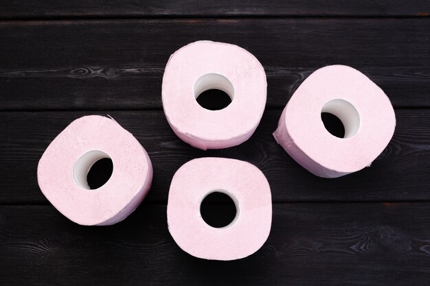 Pastelowe różowe rolki papieru toaletowego na czarnym drewnianym stole