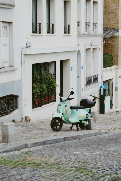 Zdjęcie pastelowy skuter zaparkowany przy cobblestone street