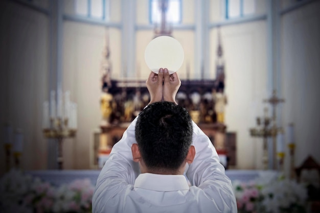 Pastor z chlebem sakramentalnym w kościele