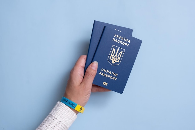 Paszporty obywatela Ukrainy w kobiecej dłoni na żółtym tle zbliżenia Napis w ukraińskiej Ukrainie Paszport