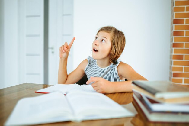 Patrząc na pracowitą dziewczynkę, podnieś palec przy biurku, odrabiając lekcje, mając wgląd, że wszystko się ułożyło