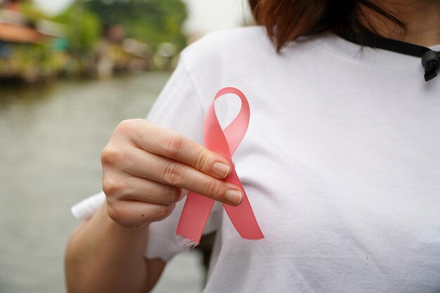 Październikowa kobieta miesiąca świadomości raka piersi w białej białej koszulce trzymająca różową wstążkę Do wsparcia