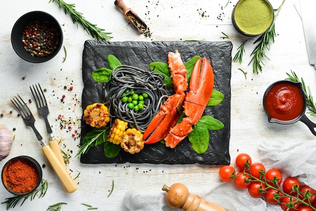 Pazur homara z czarnym makaronem i warzywami na czarnej kamiennej płycie Owoce morza Widok z góry Wolne miejsce na tekst