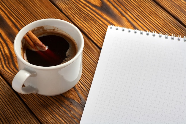 Zdjęcie pęczek cynamonu z sznurkiem, filiżanka kawy i notatnik