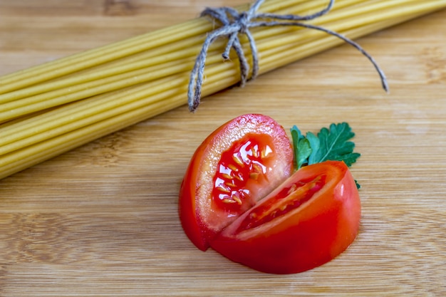 Pęczek niegotowanego makaronu spaghetti pełnoziarnistego z pomidorami, garlikiem i zieleniną