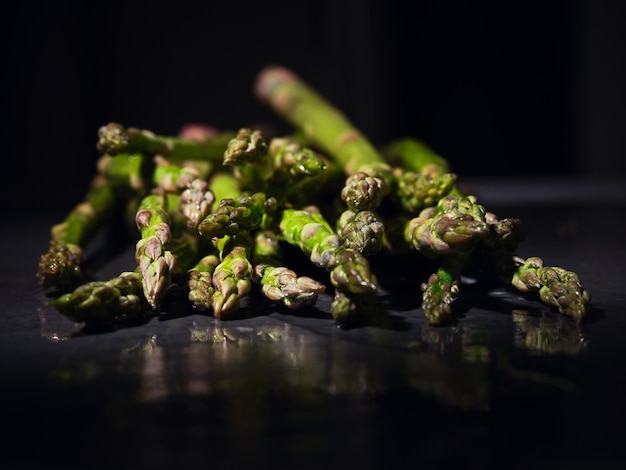 Pęczek zielonych łodyg szparagów witaminowych odbijających się na szarym stole przygotowanym do gotowania dania wegańskiego