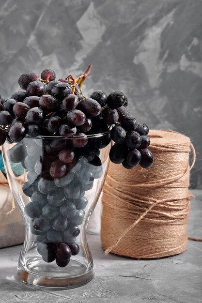 Pęczki świeżych dojrzałych czerwonych winogron na betonowej powierzchni teksturalnej