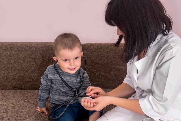 Pediatra bawi się z małym chłopcem i stetoskopem