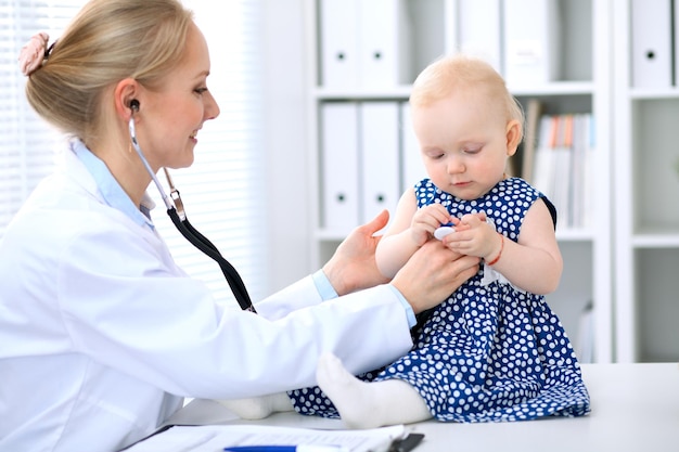 Pediatra opiekuje się dzieckiem w szpitalu. Mała dziewczynka jest badana przez lekarza stetoskopem. Koncepcja opieki zdrowotnej, ubezpieczenia i pomocy.