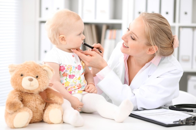 Zdjęcie pediatra opiekuje się dzieckiem w szpitalu. mała dziewczynka jest badana przez lekarza stetoskopem. koncepcja opieki zdrowotnej, ubezpieczenia i pomocy.