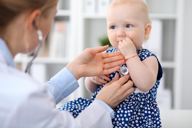 Pediatra opiekuje się dzieckiem w szpitalu. Mała dziewczynka jest badana przez lekarza stetoskopem. Koncepcja opieki zdrowotnej, ubezpieczenia i pomocy.