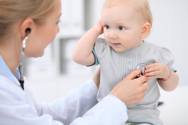 Pediatra opiekuje się dzieckiem w szpitalu Mała dziewczynka jest badana przez lekarza stetoskopem