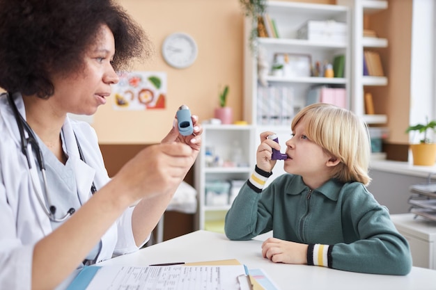 Zdjęcie pediatryka uczy małego chłopca używania inhalatora w gabinecie lekarskim