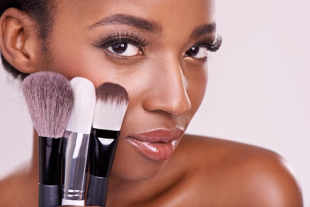Pędzle do makijażu do pielęgnacji skóry i portret czarnej kobiety z pędzlem na twarzy w studio z narzędziem do aplikacji kosmetyków Rumieniec do pielęgnacji skóry i model urody kosmetyków z luksusowym proszkiem na różowym tle