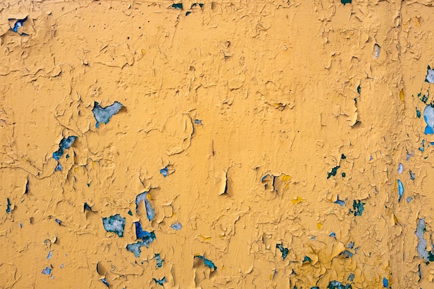 Pęknięta żółta farba na niebieskiej betonowej ścianie