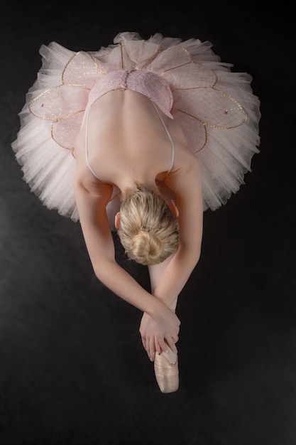 Zdjęcie pełen wdzięku balerina pochyla się do przodu w różowej spódniczce baletnicy
