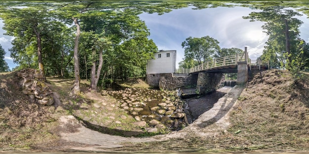 Pełna bezszwowa sferyczna panorama HDR 360 stopni kąt widzenia w pobliżu tamy wśród krzewów i drzew lasu w pobliżu małej rzeki w projekcji równoprostokątnej gotowa zawartość wirtualnej rzeczywistości VR AR