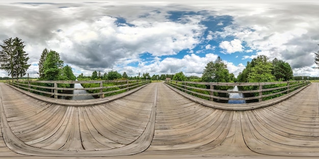 Pełna bezszwowa sferyczna panorama HDR 360 stopni kąta widzenia na drewnianym moście nad kanałem rzecznym w rzucie prostokątnym Zawartość VR AR