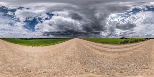 Pełna bezszwowa sferyczna panorama hdri 360-stopniowy widok na szutrową drogę bez ruchu wśród pól z zachmurzonym niebem przed burzą w projekcji równoprostokątnej gotowy na zawartość VR AR w rzeczywistości wirtualnej