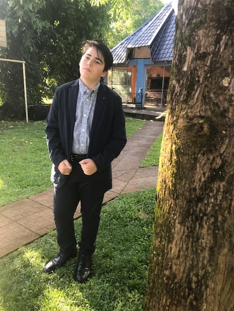 Zdjęcie pełna długość chłopca stojącego przy drzewie przeciwko domowi