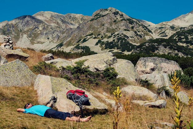 Zdjęcie pełna długość człowieka leżącego na polu na tle pasma górskiego