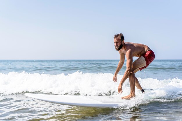 Zdjęcie pełna długość człowieka surfującego w morzu przeciwko niebu