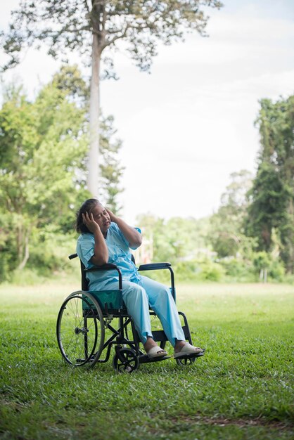 Pełna długość dojrzałej kobiety siedzącej na wózku inwalidzkim w parku