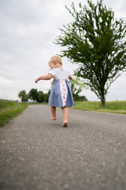 Zdjęcie pełna długość dziewczyny biegnącej po drodze przeciwko niebu