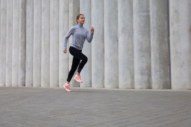 Pełna długość młoda sportowa kobieta jogging podczas ćwiczeń na świeżym powietrzu.