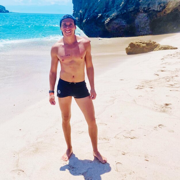 Pełna długość młodego mężczyzny stojącego na plaży