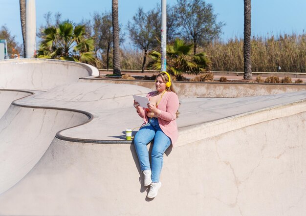 Zdjęcie pełna długość młodej kobiety siedzącej w parku na deskorolce
